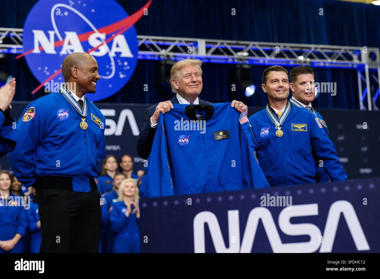Präsident Donald J. Trump hält eine personalisierte NASA-Flugjacke, die ihm während der Congressional Space Medal of Honor Zeremonie im Johnson Space Center der NASA in Houston, Texas, am 28. August 2026 überreicht wurde. Artemis-II-Astronauten Victor Glover, Reid Wiseman und Jeremy Hansen stehen neben dem Präsidenten. Bild mit freundlicher Genehmigung des Weißen Hauses. Stockfoto