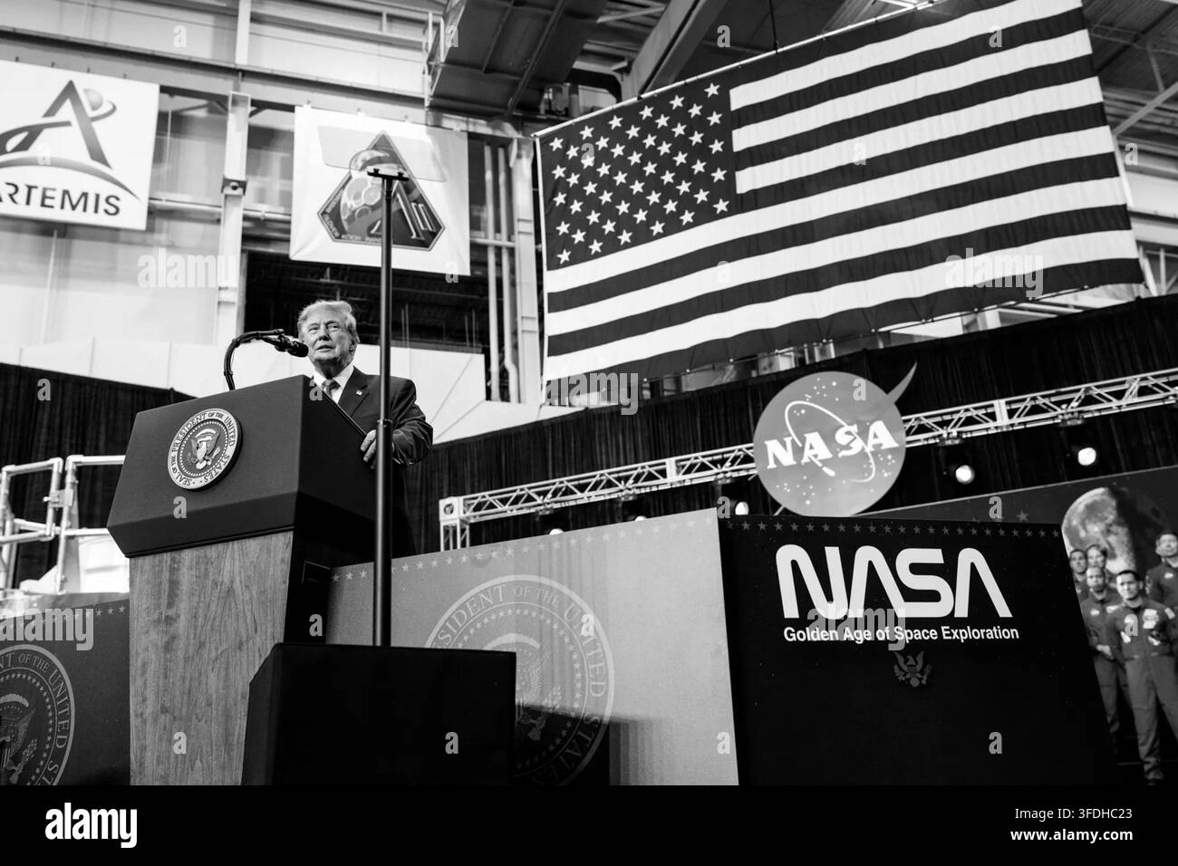 Präsident Donald J. Trump hält eine Rede unter einer großen amerikanischen Flagge während der Congressional Space Medal of Honor Zeremonie im Johnson Space Center der NASA in Houston, Texas, am 28. August 2026. Das Schwarz-Weiß-Foto zeigt NASA- und Artemis-Bilder, die das Präsidentenpodium umgeben. Bild mit freundlicher Genehmigung des Weißen Hauses. Stockfoto