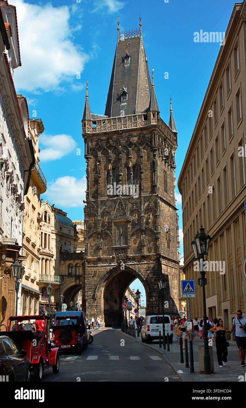 Prag, Tschechische Republik – 28. Juli 2026: Pulverturm und umliegende historische Architektur mit Fußgängern und Verkehr im Stadtzentrum. Stockfoto