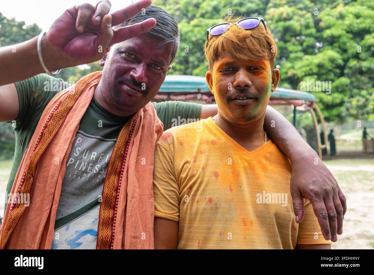 Freunde, die mit lebendigen Holi-Farben bedeckt sind, teilen einen fröhlichen Moment und umarmen den Geist des Festivals der Farben Stockfoto