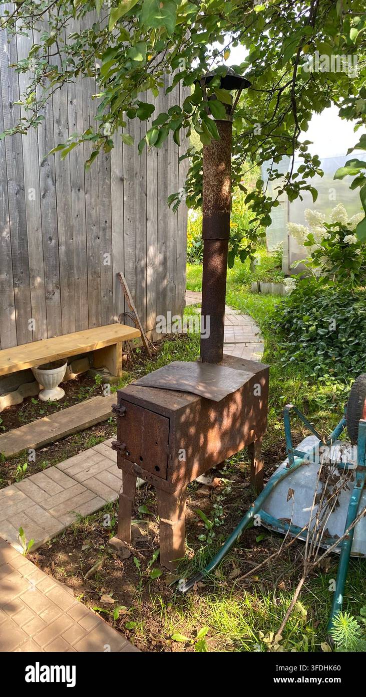 Rostiger alter Holzofen mit Schornstein in einem ländlichen Garten Stockfoto