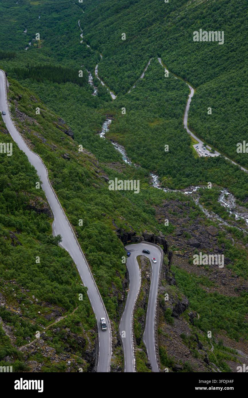 Drohnenperspektive einer sich windenden Bergstraße, die sich durch dichten grünen Wald schneidet, mit einer engen Spitzkehre, sichtbar ist eine Flussschlucht. Stockfoto