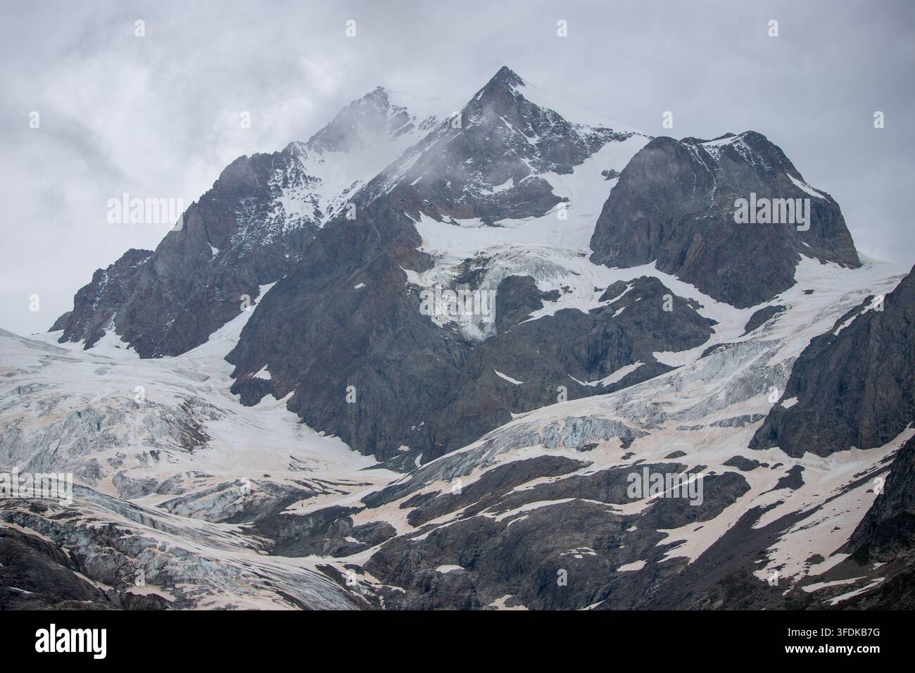 Blick auf das Massiccio del Monte Bianco mit seinen schneebedeckten Gipfeln, Gletschern und schroffen Felshängen unter einem bewölkten Himmel in der Valle d'Aosta, Italien. Stockfoto