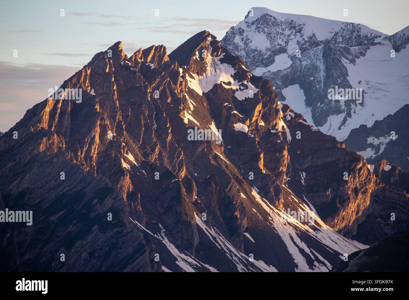 Blick auf die schroffen, schneebedeckten Gipfel des Massiccio del Monte Bianco, die vom warmen goldenen Licht des Sonnenaufgangs in der Valle d'Aosta, Italien, beleuchtet werden. Stockfoto