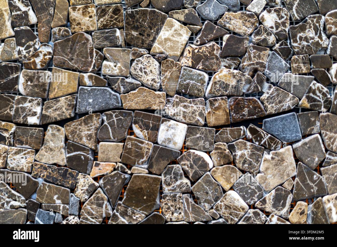 Braune und graue natürliche Steinmosaiktextur. Unregelmäßige polierte Steinmosaikteile in Braun, Grau, Beige und Weiß mit natürlicher Maserung und variiert Stockfoto