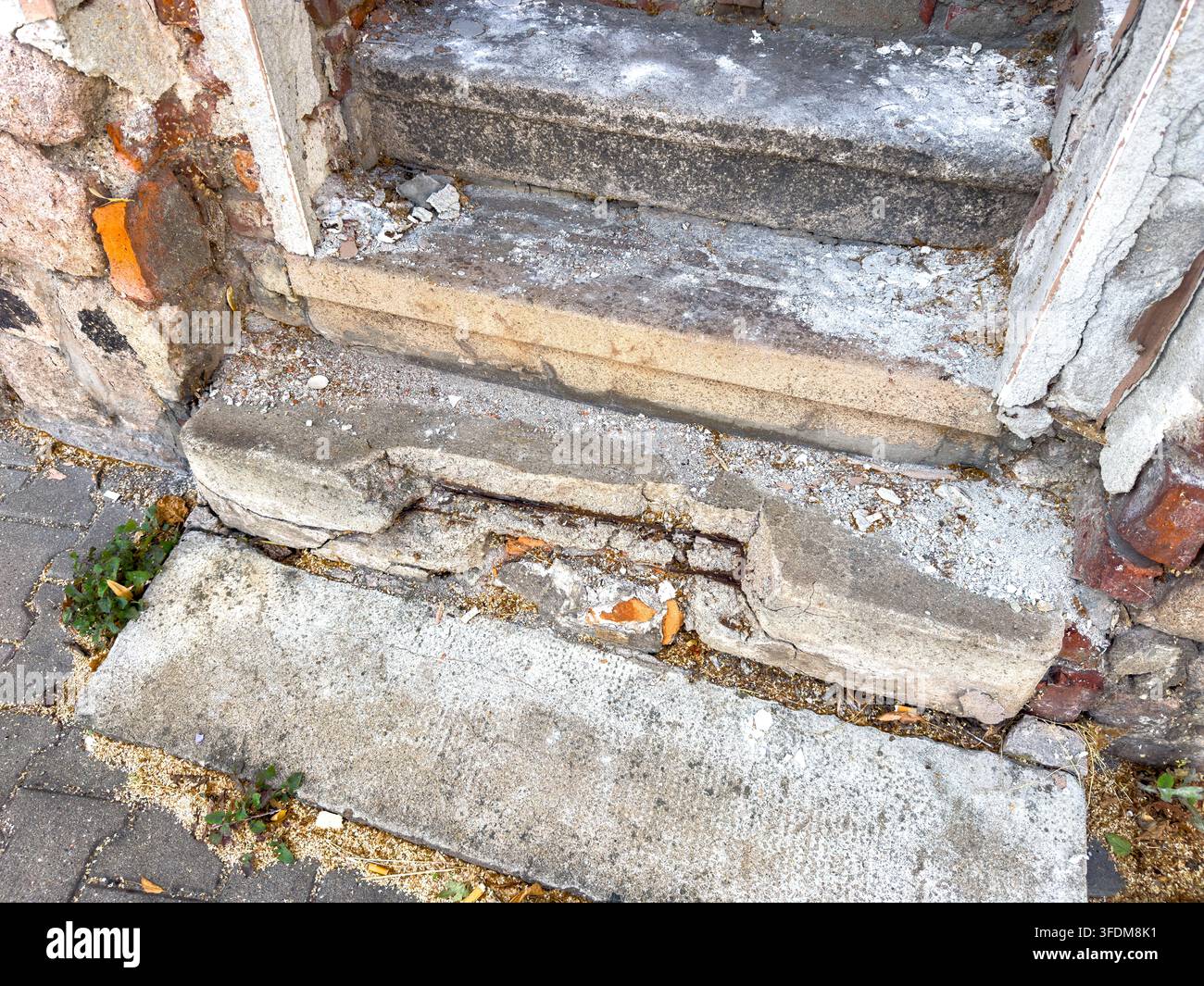 Alte, abgenutzte und baufällige Eingangstreppe eines Wohngebäudes, die Anzeichen von Alter, Witterungseinflüssen und Verschlechterung aufweist. Das vernachlässigte Äußere betont Stockfoto
