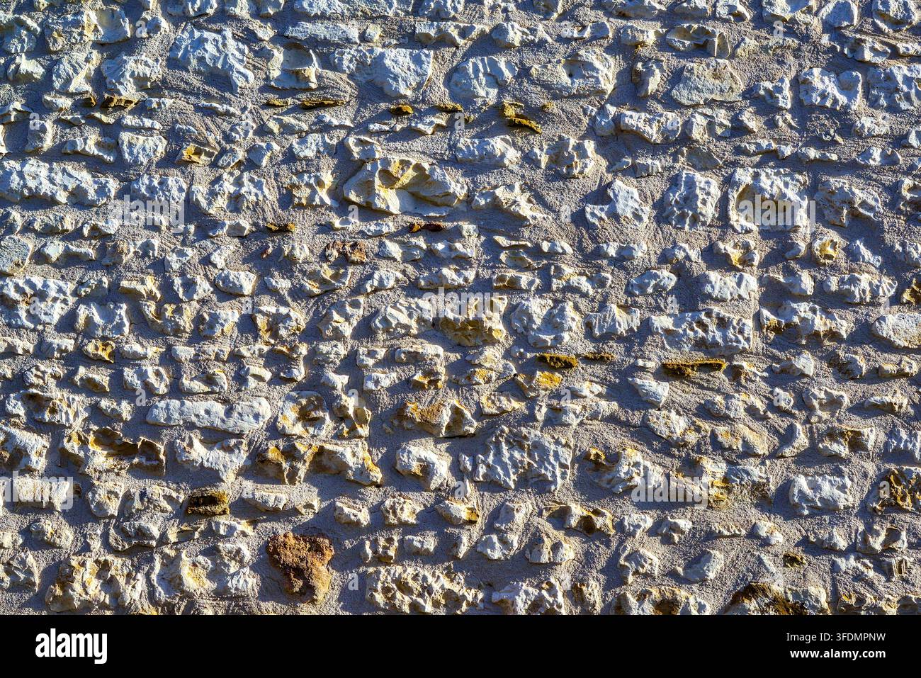 Alte Steinmauer eines Hauses, die durch seitliches Licht ihre Textur offenbart – Ligueil, Indre-et-Loire (37), Frankreich. Stockfoto