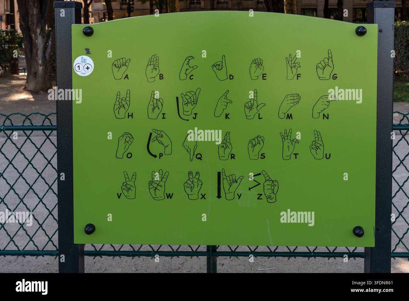 Grünes Schild mit dem Gebärdensprachalphabet von A bis Z mit illustrierten Handgesten. Pädagogisches Gebärdensprachendiagramm auf einem Spielplatz Stockfoto