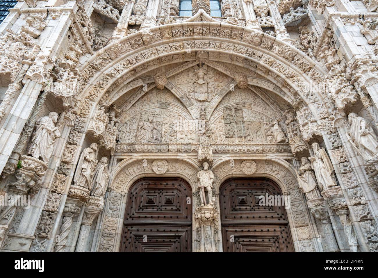 Aufwendiges steinernes Portal mit Statuen, Bögen und dekorativen Reliefs an einer historischen Kirchenfassade in Lissabon, Portugal. Reichhaltige Textur und Architektur Stockfoto