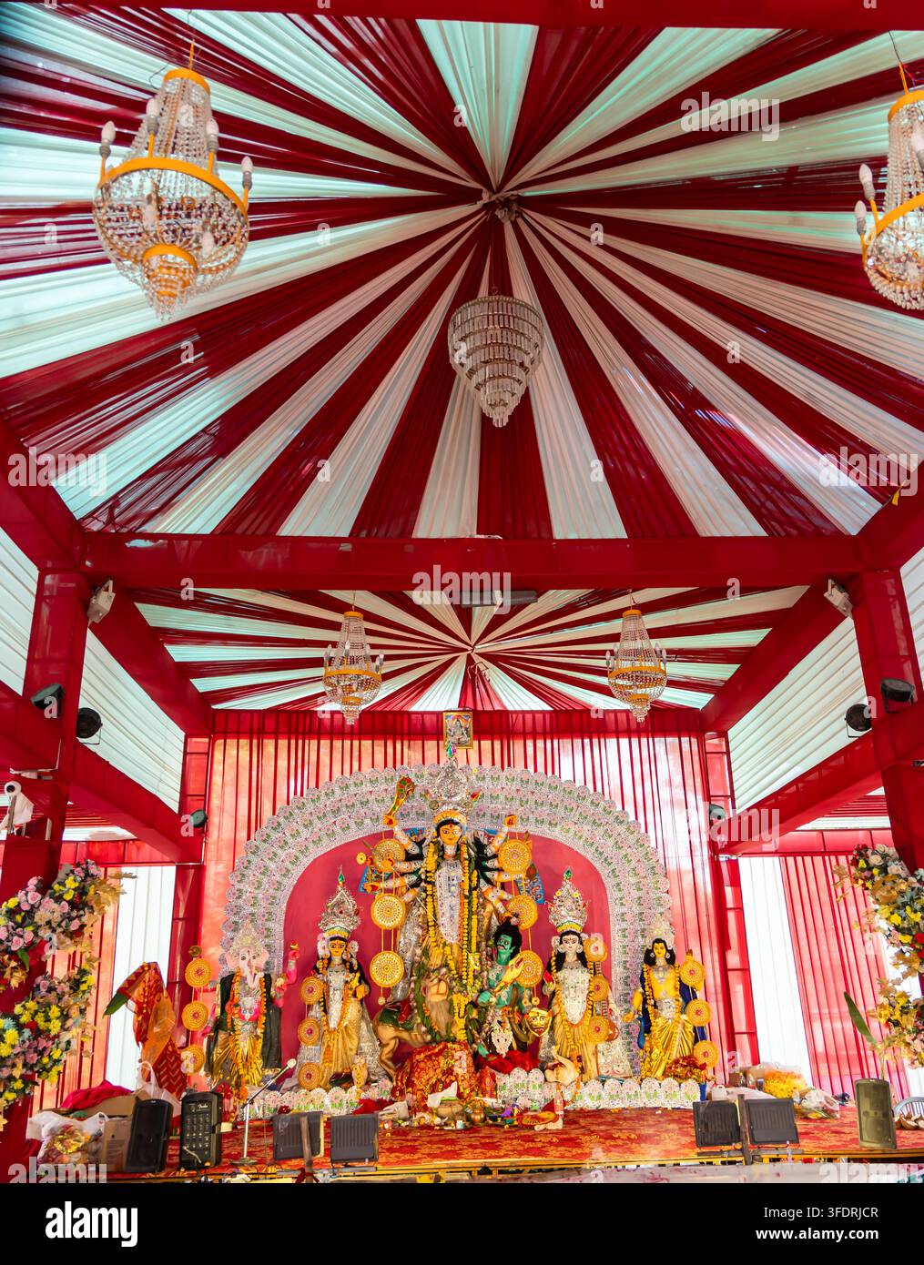 Göttin-Durga-Statue im Inneren eines Durga-Puja-Pandal mit Blumendekorationen und Kronleuchtern Stockfoto