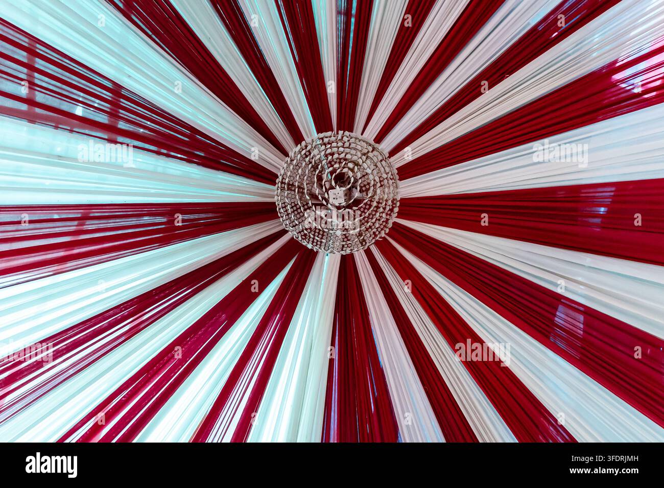 Durga Puja Pandal-Decke mit Kronleuchter aus rotem und weißem Stoff und bunten Vorhängen dekoriert Stockfoto