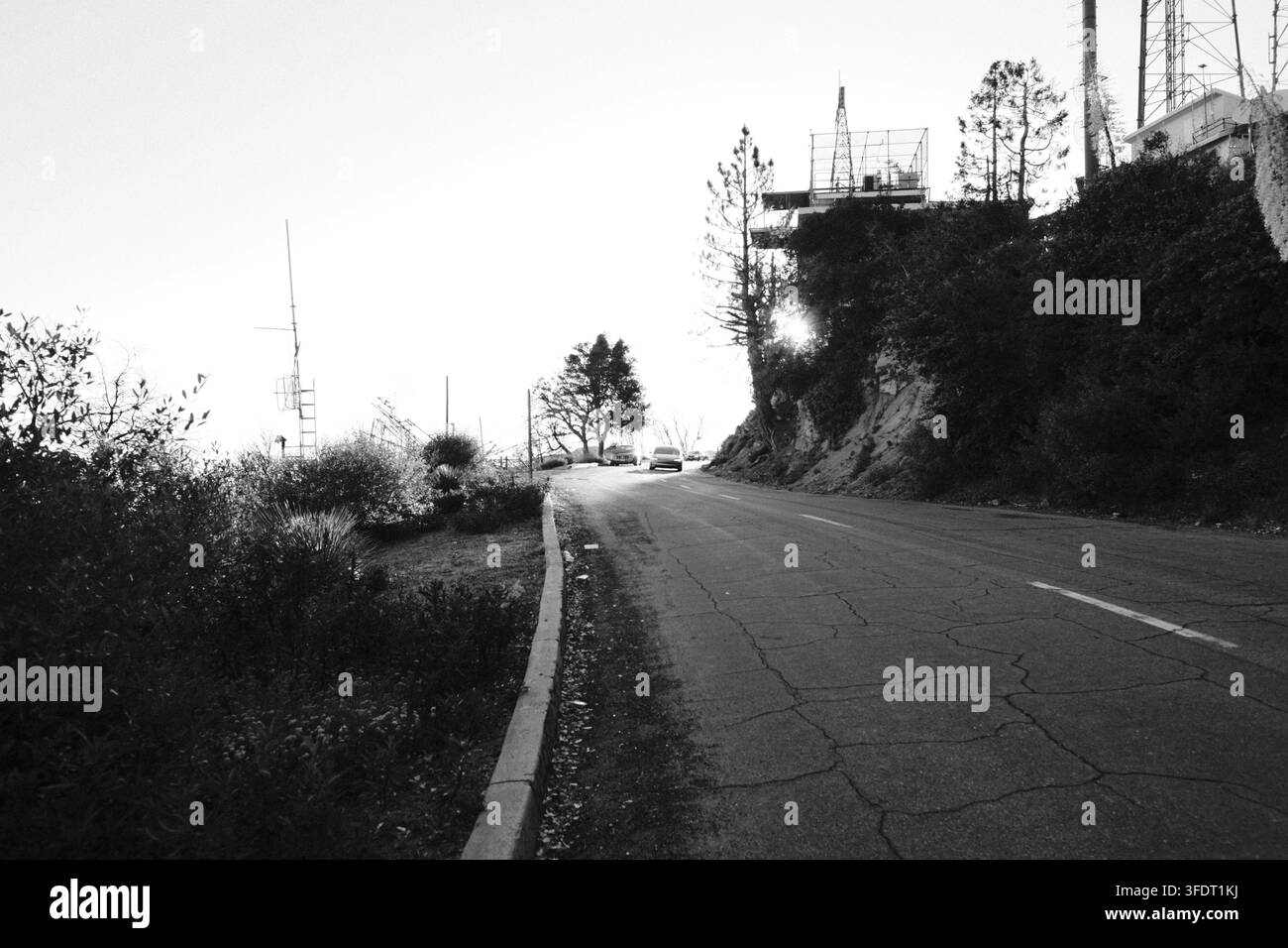 Ruhige gepflasterte Straße, die durch das hügelige Mt. Wilson mit Strommasten und Vegetation in Südkalifornien verläuft. Nach den Bränden. Stockfoto