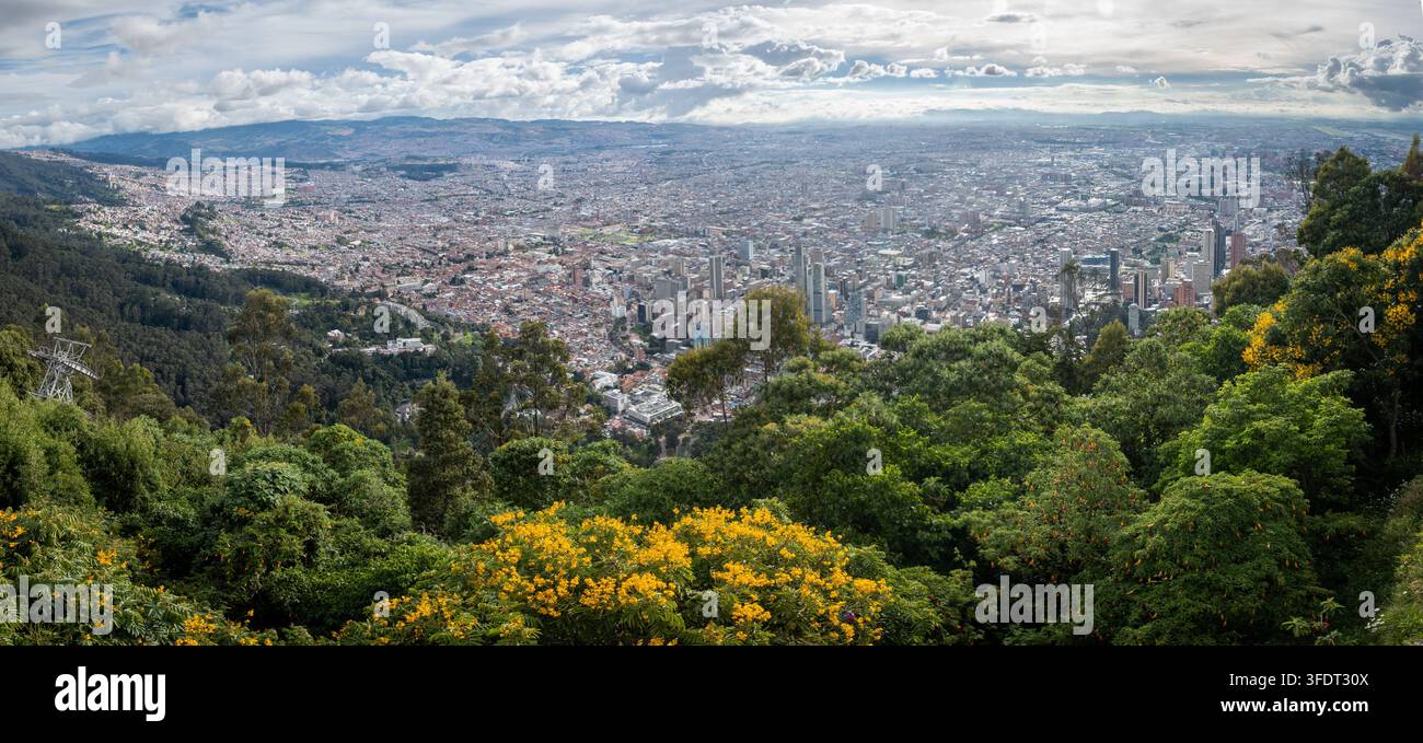 Breite Panoramaansicht von Bogotá, Kolumbien, von Monserrate mit dichter urbaner Skyline, umliegenden Anden und üppiger Vegetation im Vordergrund. Dramati Stockfoto