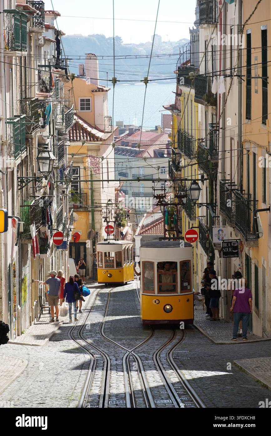 Historische gelbe Straßenbahn fährt durch eine steile Straße in Lissabon, Portugal Stockfoto