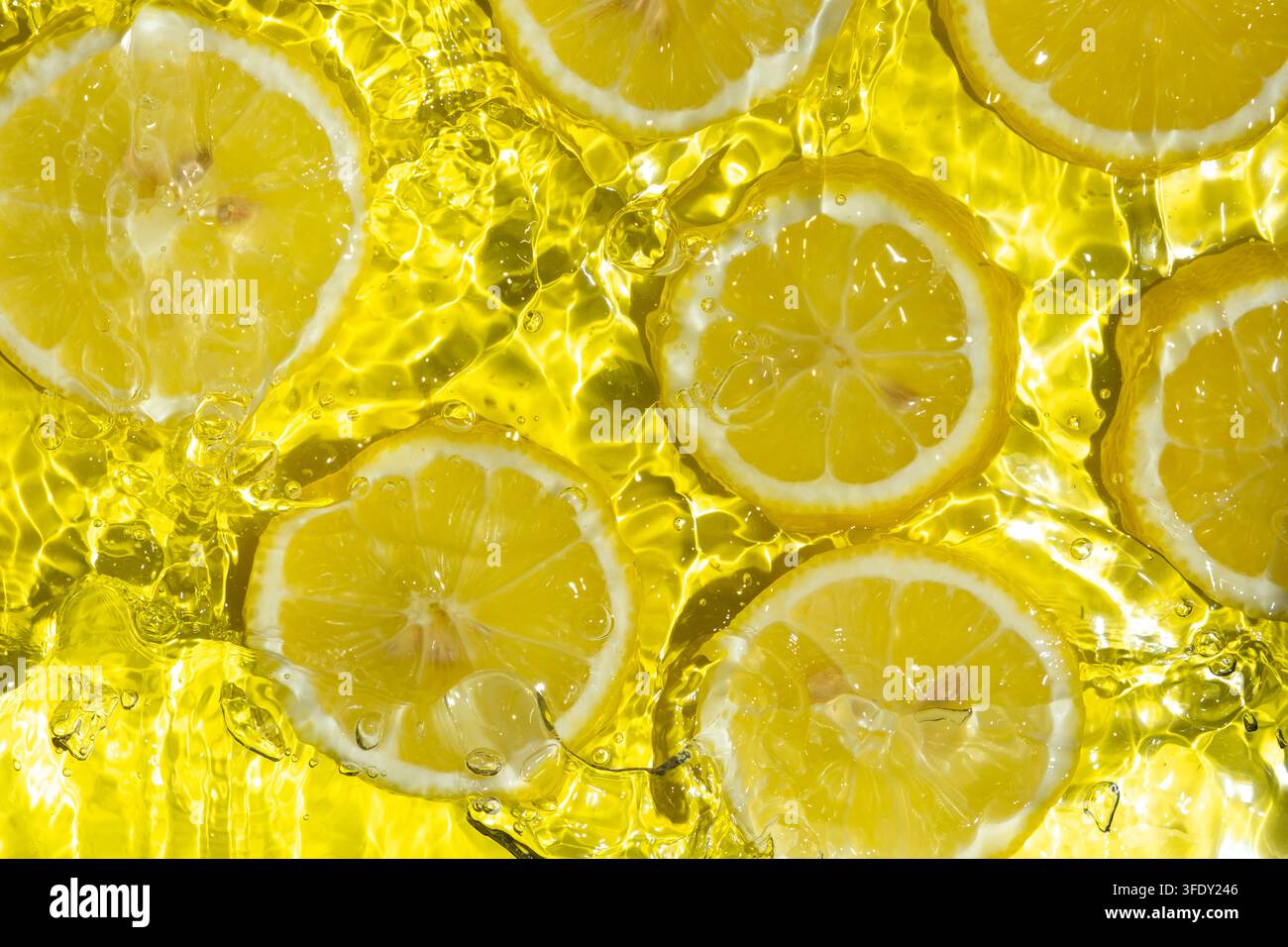 Frische Zitronenscheiben spritzen vor hellem Wasserhintergrund Stockfoto