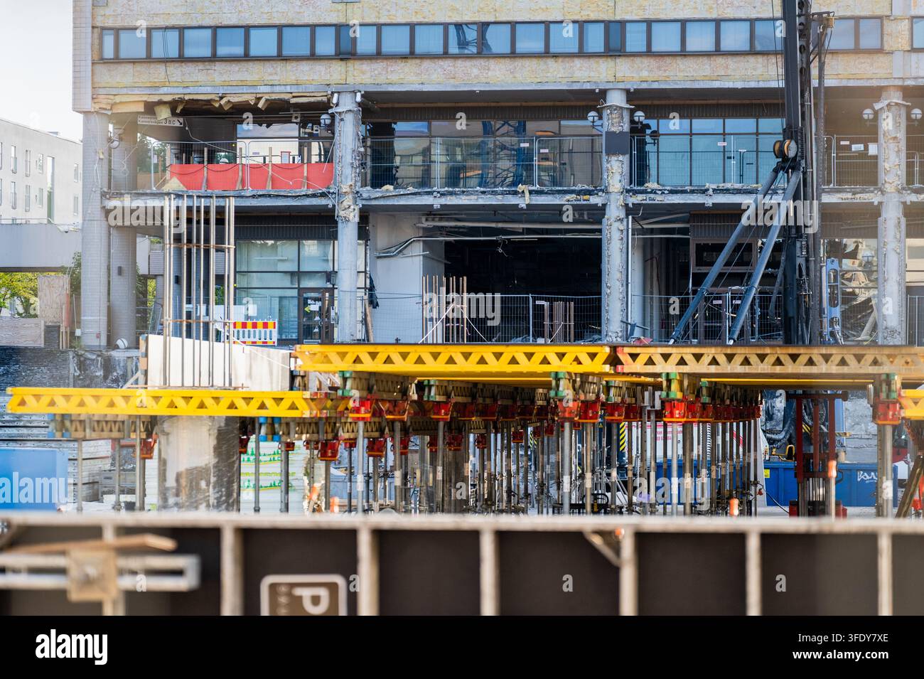 Großes Gebäude unter Renovierung mit Betonstützen und vorübergehenden Baustrukturen auf einer städtischen Baustelle Stockfoto