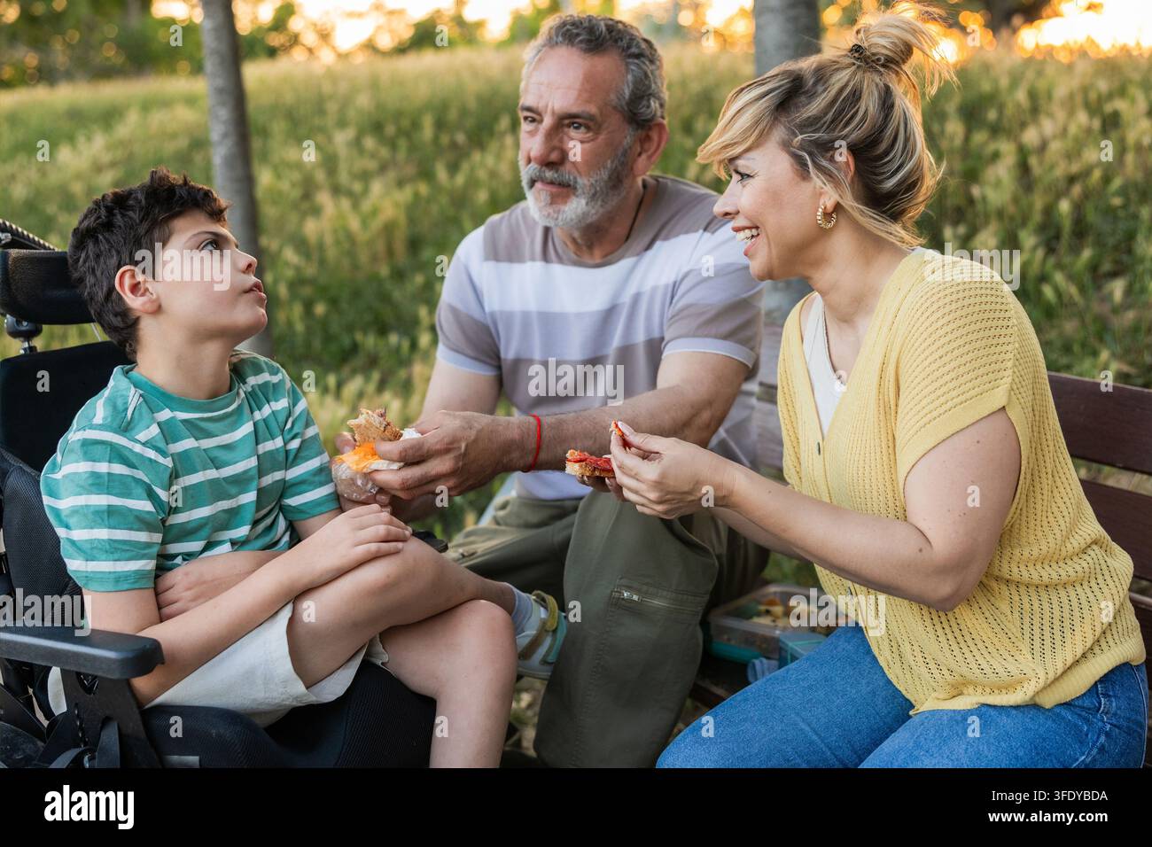 Familie genießt Snacks im Freien mit Enkel in einem Rollstuhl Stockfoto