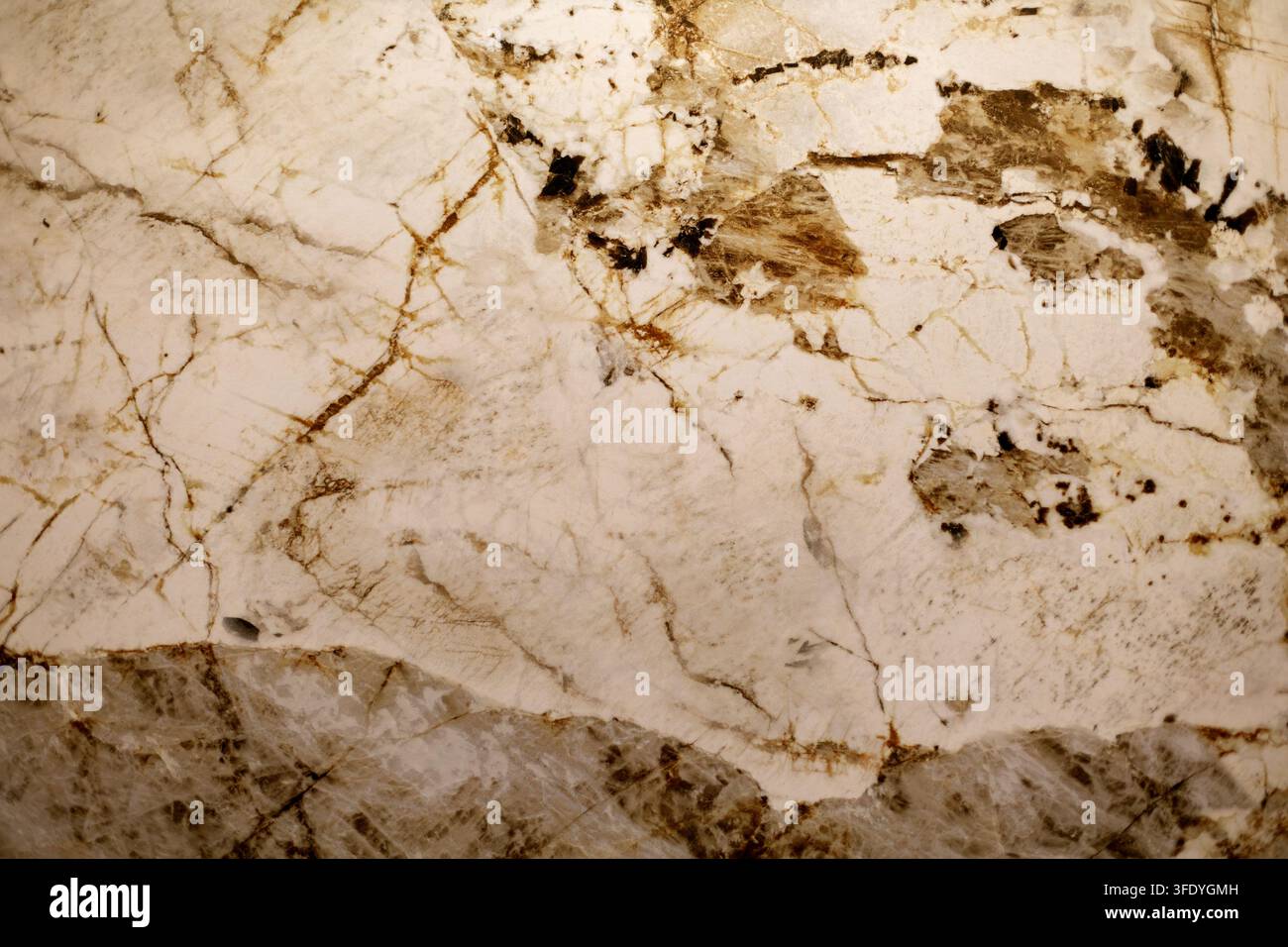 Cremige Steinstruktur mit braunen Mineralverläufen. Nahaufnahme von cremefarbenem Naturstein mit braunen Adern und kristallinen Mineralmustern. Stockfoto
