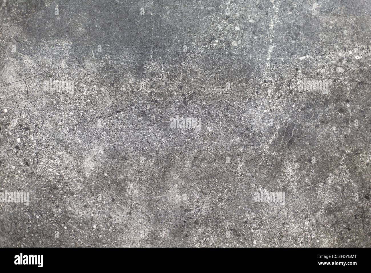 Dunkle graue Steintextur mit weißen Sprenkeln. Nahaufnahme von dunklem grauem Stein mit weißen Sprenkeln, Kratzern und gesprenkelter Oberflächenstruktur. Stockfoto