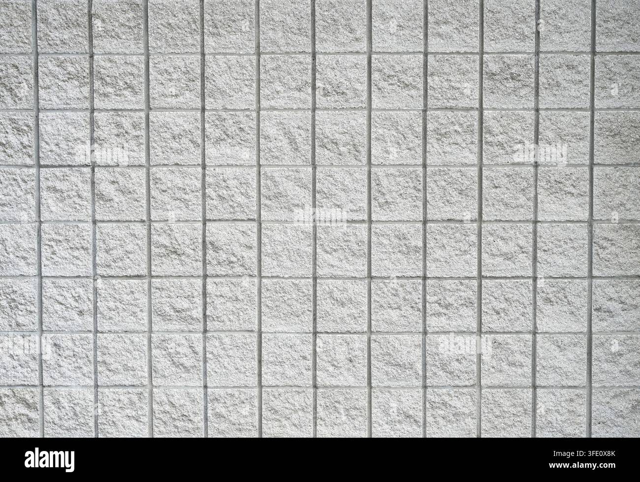 Weiße quadratische Ziegel-Mauer mit Mörtel, die ein Rastermuster zeigt mit grob geschnittenen Ziegelflächen und glatten, gleichmäßigen Fugen über die horizontale Oberfläche Stockfoto
