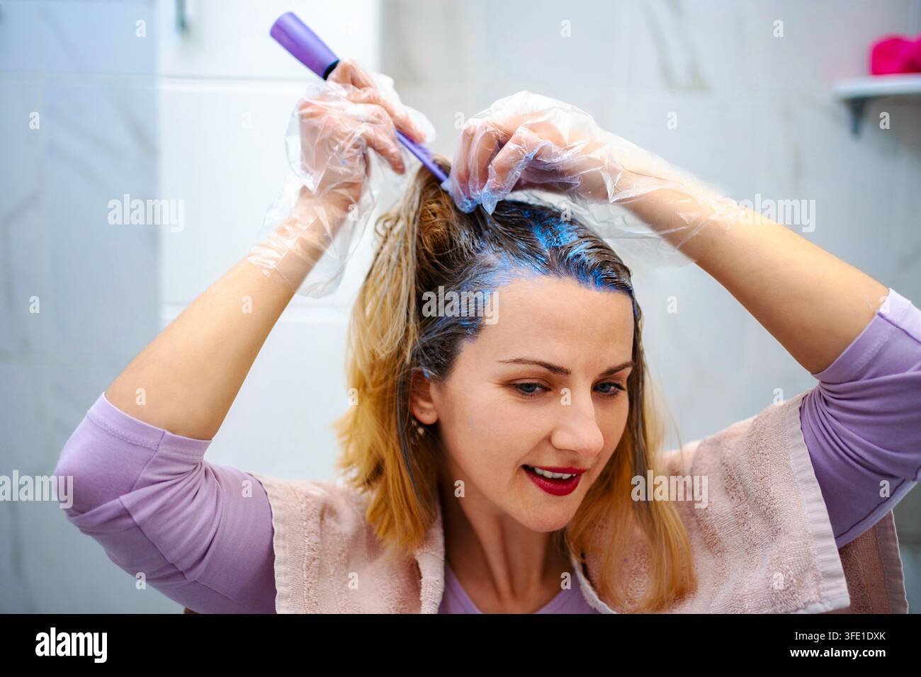 Frau, die zu Hause blaue Haarfarbe aufträgt Stockfoto
