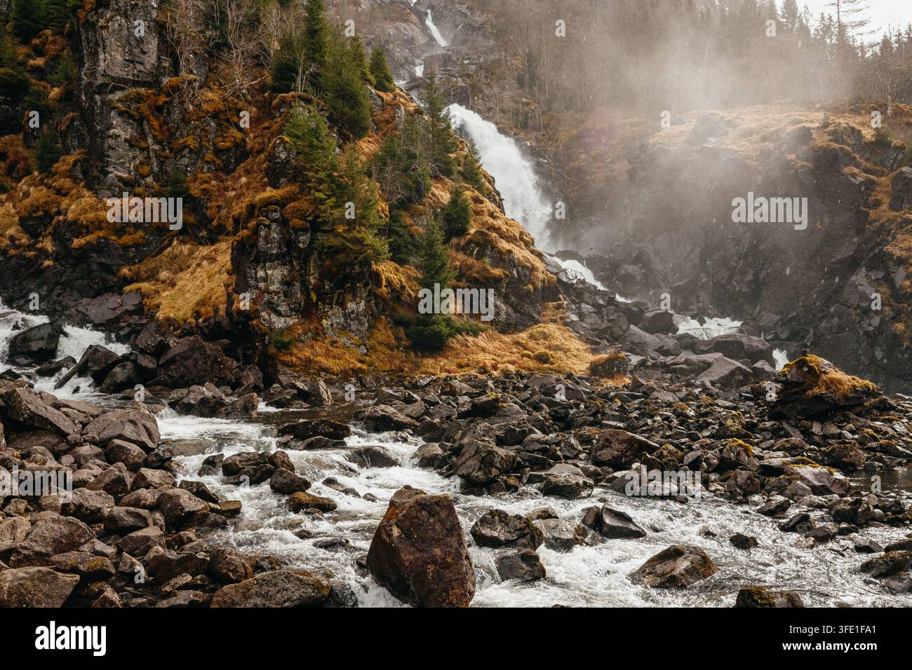 Eine stimmungsvolle, dramatische Herbstansicht des berühmten Latefossen-Wasserfalls, der unter einer historischen Steinbogenbrücke auf der Route 13 in Norwegen hinabstürzt. Stockfoto