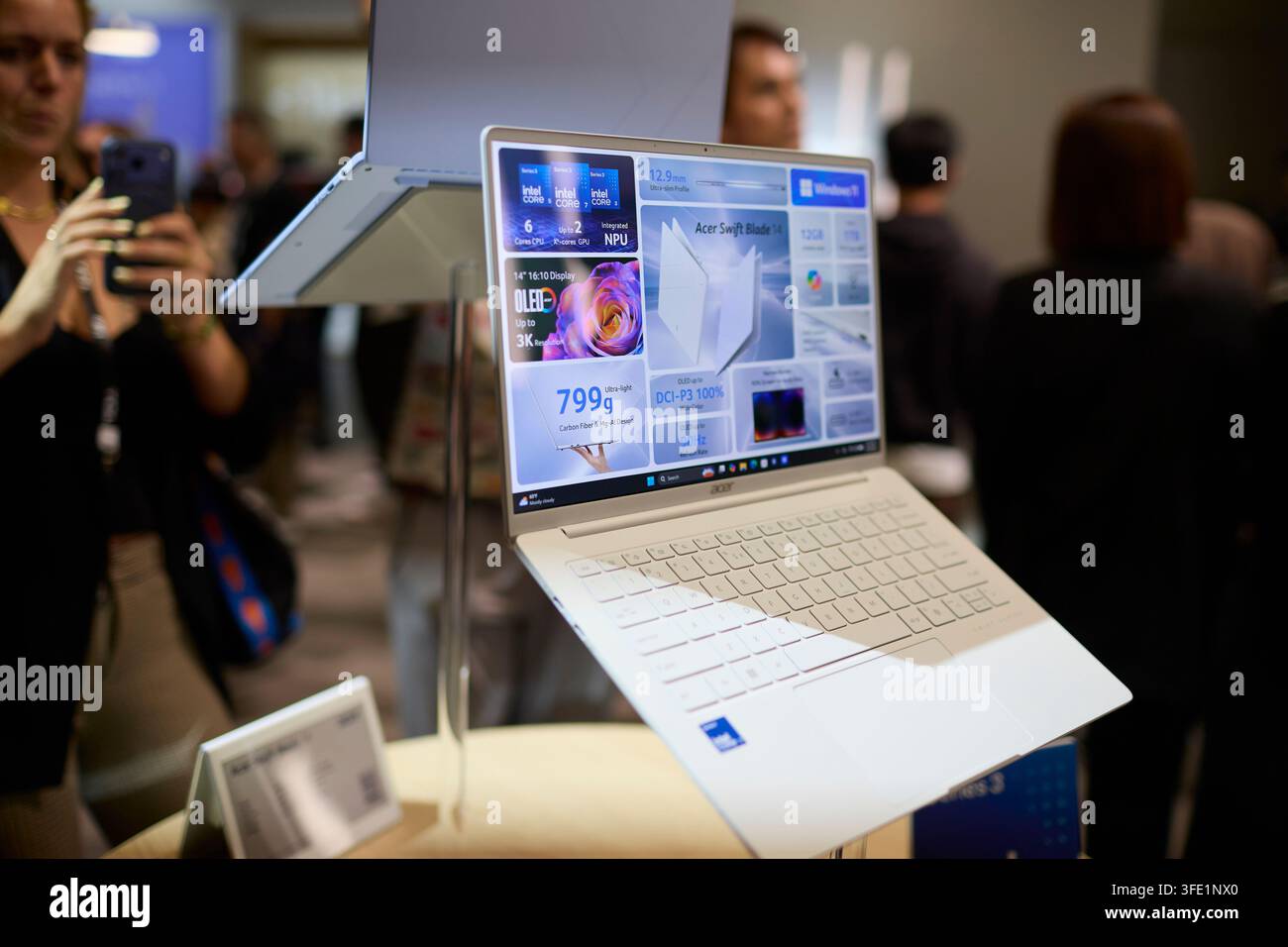 Berlin, Deutschland, 2. Sep., 2026. Nahaufnahme des neu angekündigten Acer Swift 14 Blade-Laptops, der auf einer Technikveranstaltung ausgestellt ist. Das leichte 799g-Gerät ist auf einem Ständer montiert und präsentiert sein weißes Gehäuse und einen aktiven 14-Zoll-3K-OLED-Bildschirm mit werblichen Spezifikationen. Im verschwommenen Hintergrund verwendet ein Journalist ein Smartphone, um ein Foto der Hardware-Demonstration zu machen, und hebt die Produktpräsentation und die Medienberichterstattung während der Elektronik-Messe hervor. Felix Wolf/Alamy Live News. Stockfoto