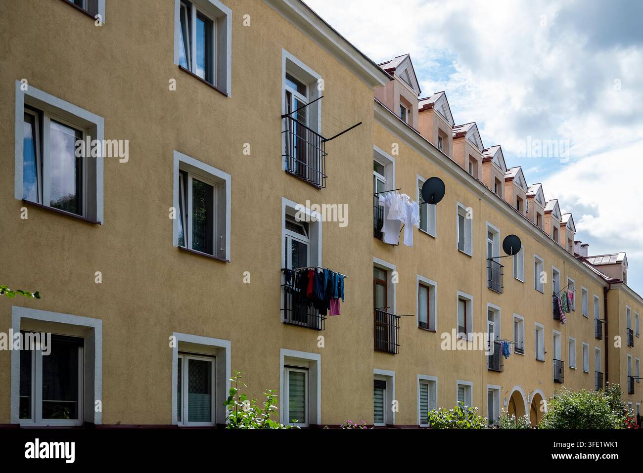 Nowa Huta, Krakau, Polen 19. August 2026 Wäsche hängt zum Trocknen auf kleinen Balkonständerchen einer gelben Wohnhausfassade in Nowa Huta Stockfoto