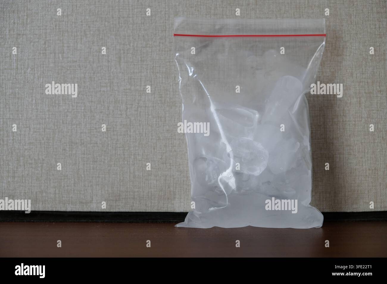 Klarer Plastik-Reißverschlussbeutel gefüllt mit Eiswürfeln auf neutralem Hintergrund Stockfoto
