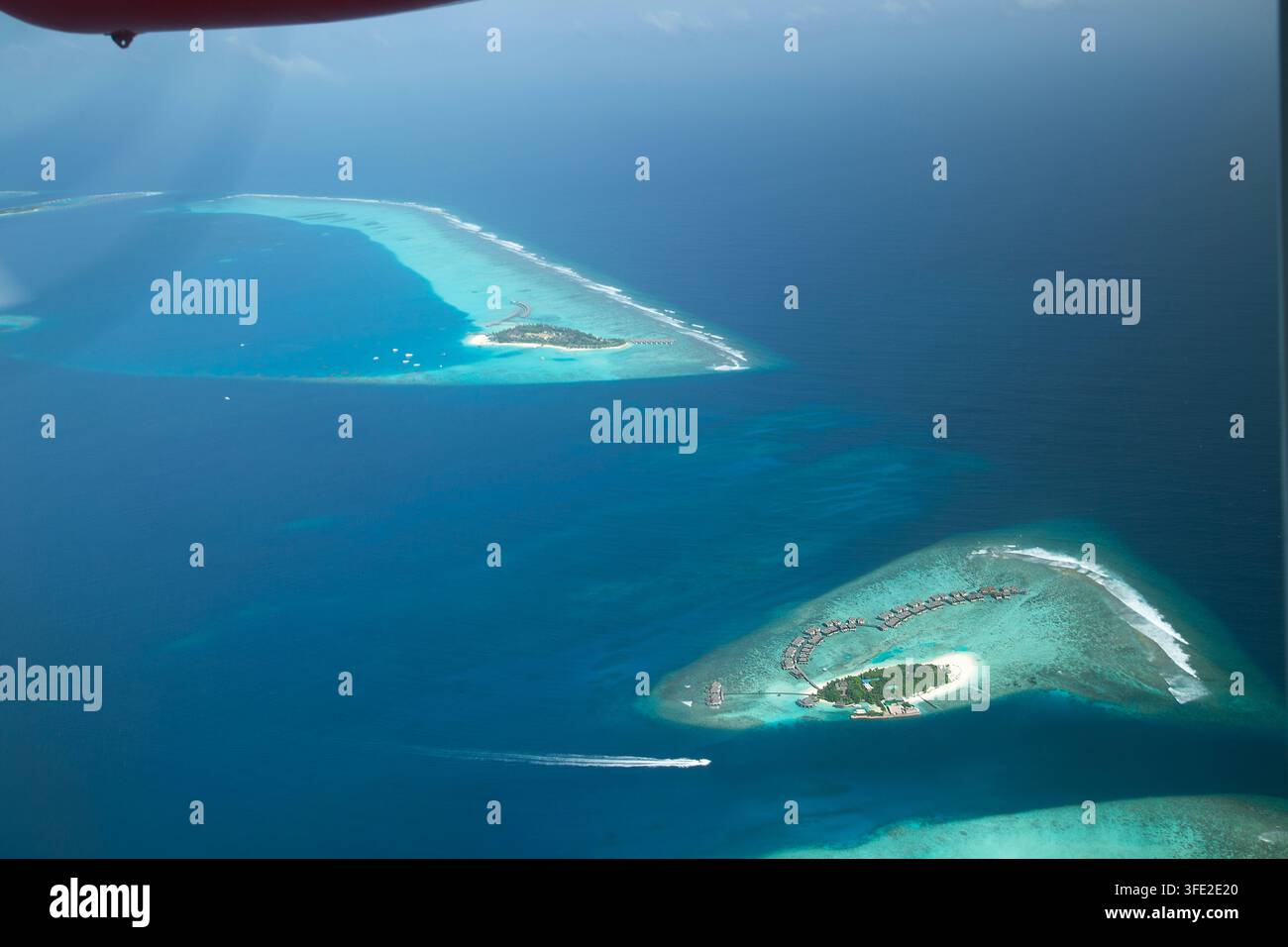 Ein atemberaubender Hochwinkel-Aerialblick auf paradiesische tropische Inseln, Wasser-Villen und lebendige Korallenriffe, umgeben von tiefblauem und klarem Tur Stockfoto