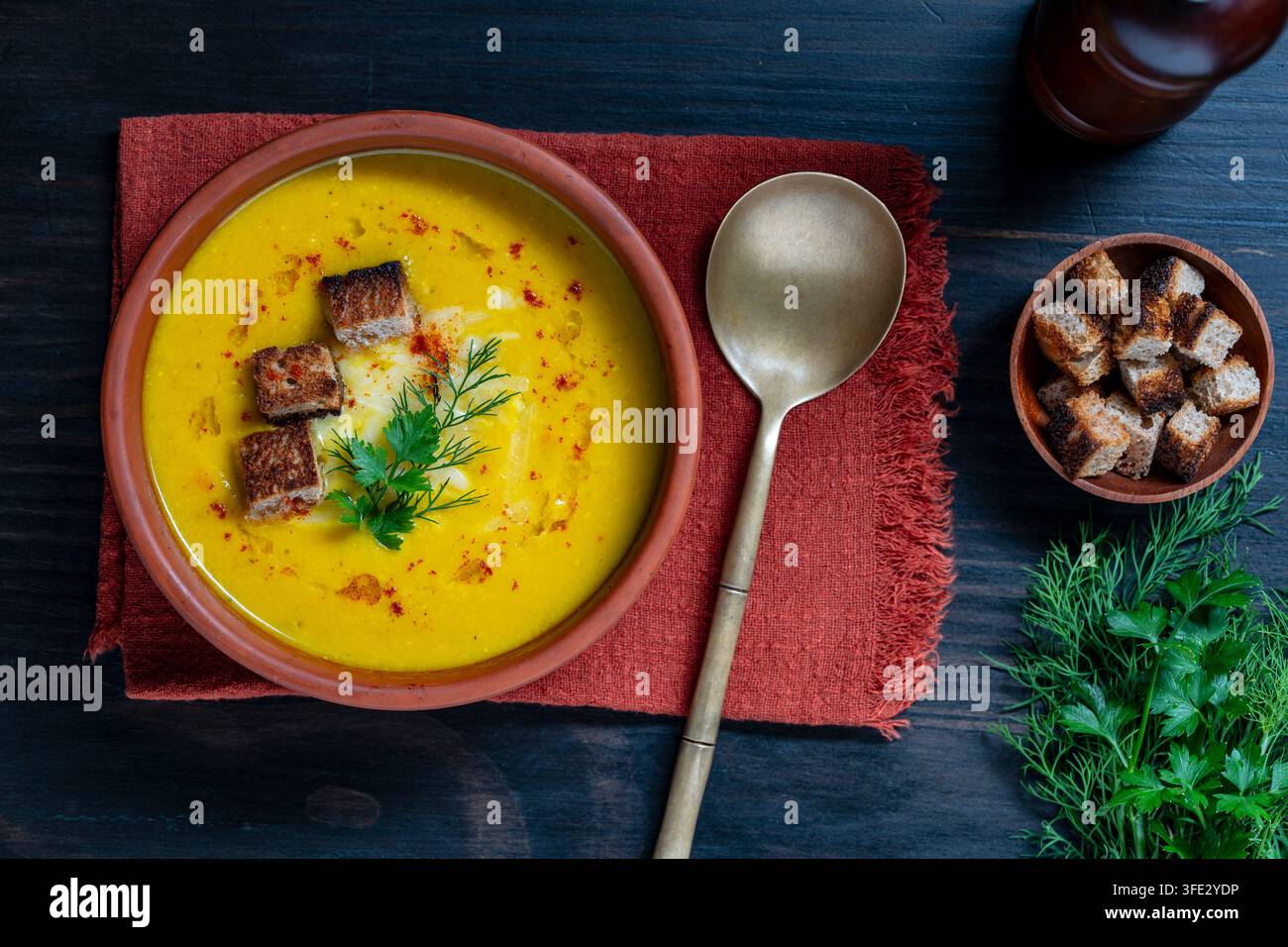 Cremige Kürbis- oder Karottensuppe mit Croutons und Kräutern, Blick von oben, Nahaufnahme. Köstliche gelbe Gemüsepüreesuppe in einer Keramikschale, serviert mit knusprigem Stockfoto