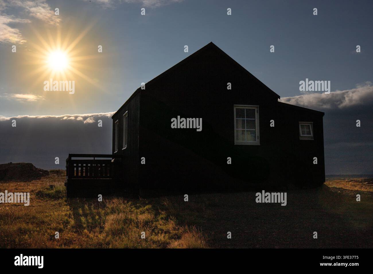 Ein schwarzes Cottage als Silhouette unter hellem Sonnenlicht Stockfoto