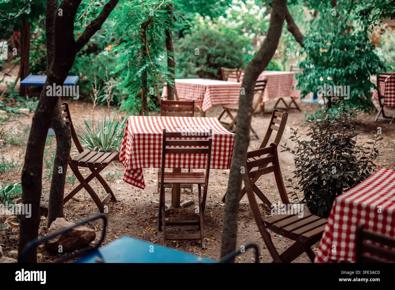 Gemütliches Gartenrestaurant mit rot karierten Tischdecken Stockfoto