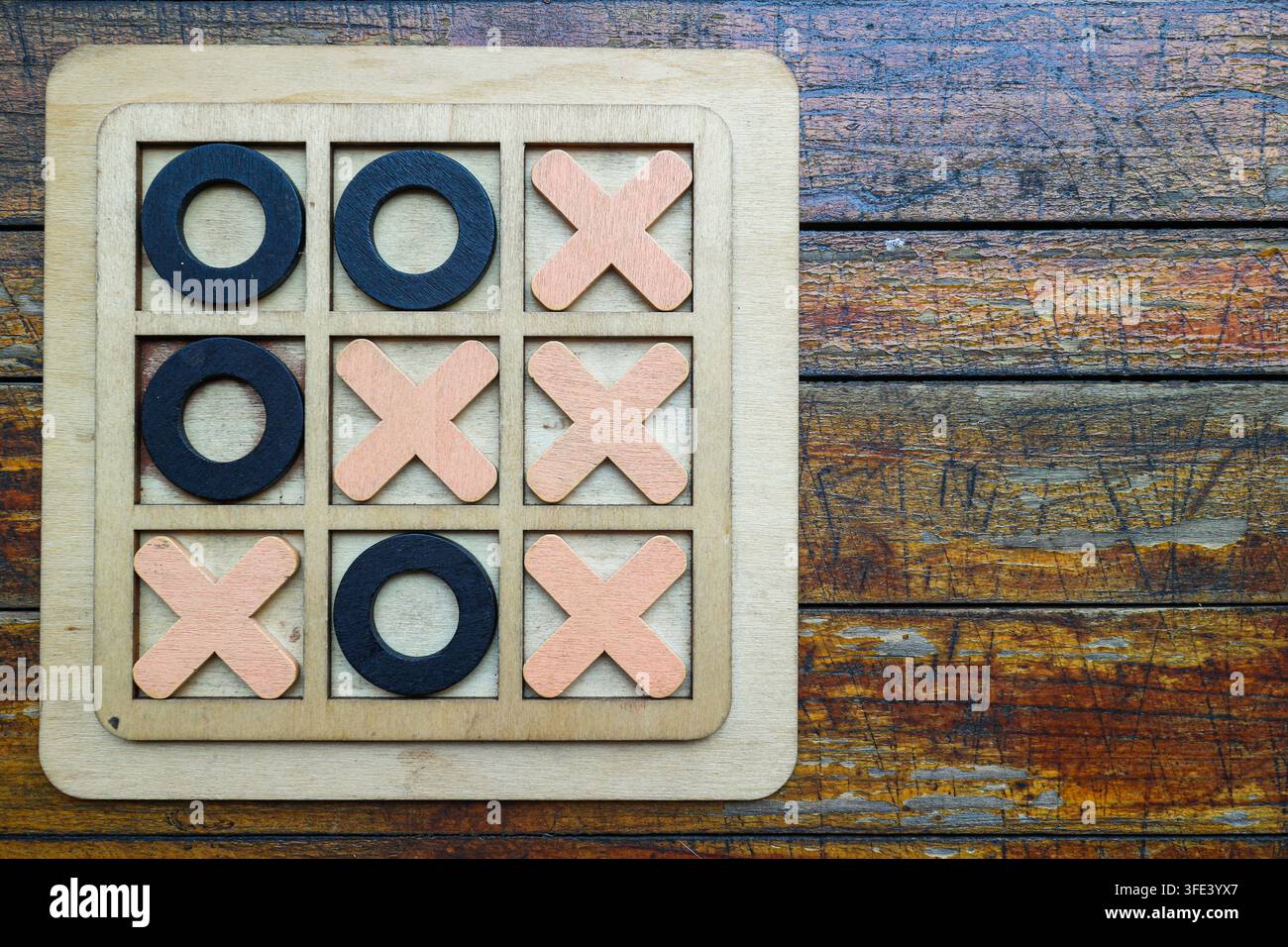 Top-Down-Flachlage eines fertigen Holz-NULL-EN-KREUZ-Spiels auf einem rustikalen Tisch mit einem diagonalen Sieg und freiem Platz auf der rechten Seite. Stockfoto