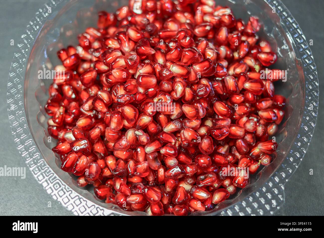 Frische rote Granatapfelkerne in einem klaren Plastik-To-Go-Behälter mit Deckel, bereit zum Mitnehmen als gesunder Obstsnack. Stockfoto