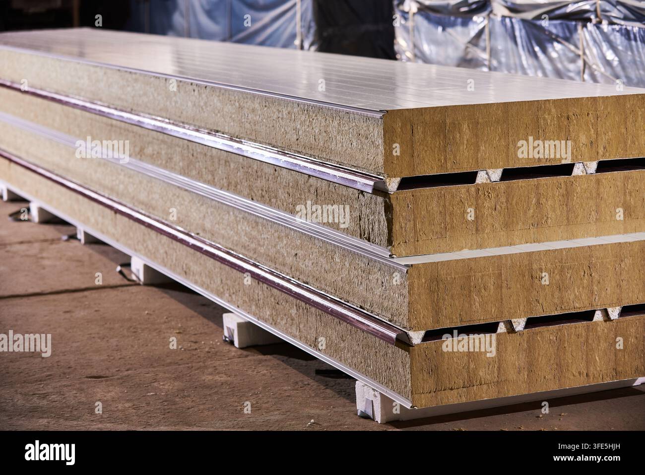 Stapel isolierter Sandwichwand- und Dachplatten mit Kern aus Gesteinswolle, gelagert auf einer Baustellenlagerfläche. Dämmstoff für Stockfoto