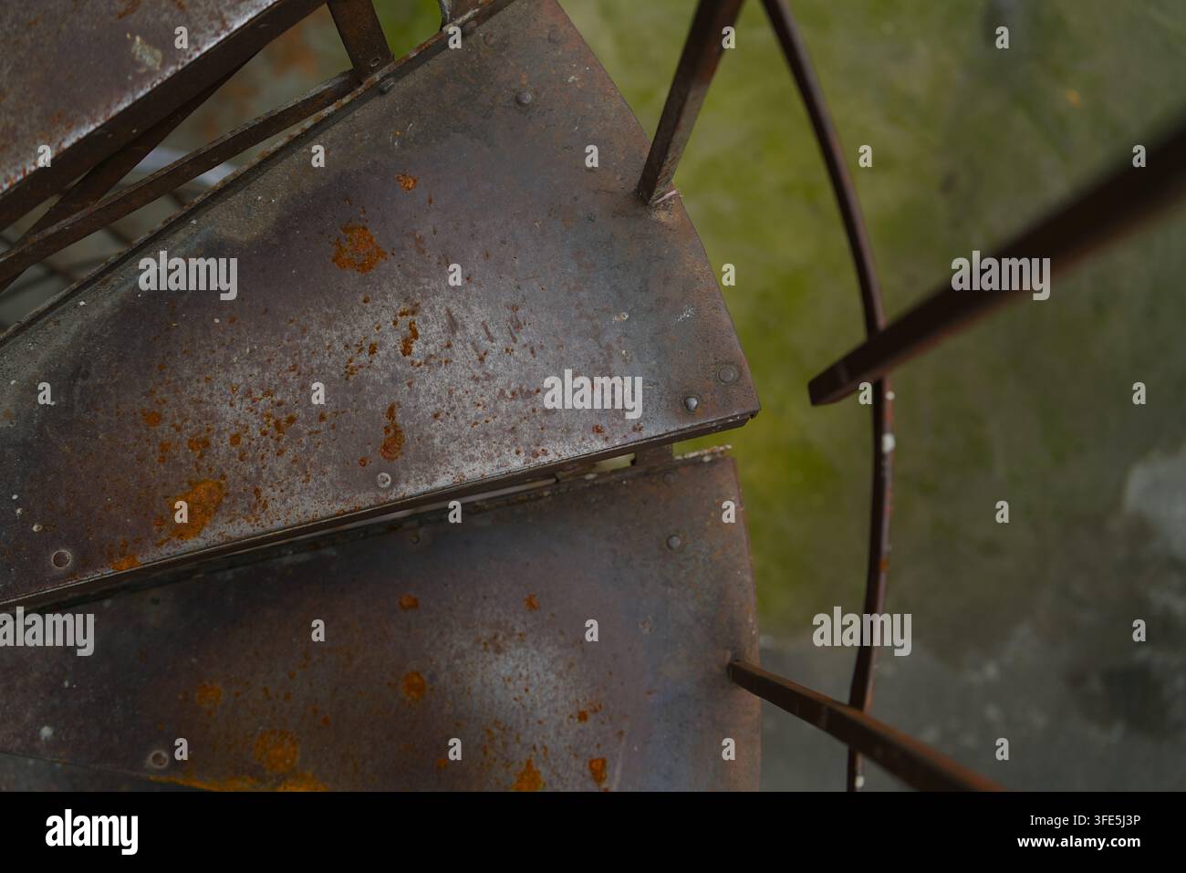 Schaut man hinunter auf alte rostige Metallstufen einer Wendeltreppe, die verwitterte Textur und industrielle Details zeigen. Stockfoto