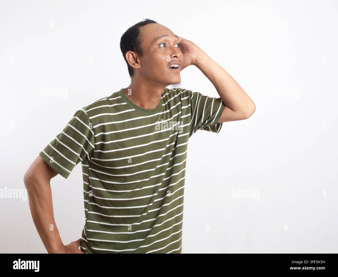 Ein Mann über isolierter Wand, der etwas hört, indem er die Hand ans Ohr legt, Mann über isolierter Wand, der etwas hört Stockfoto