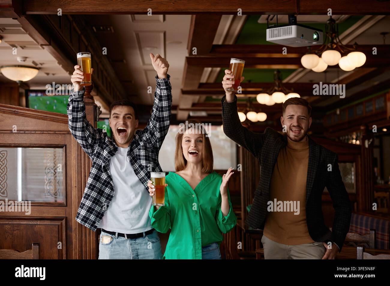 Freunde feiern mit erhobenen Bieren, junge Kollegen und Unterstützer Stockfoto