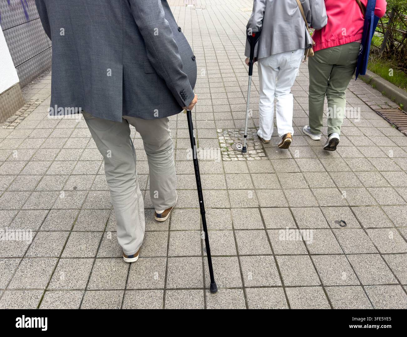 Ältere Menschen gehen auf einem Fußweg mit Gehstütze Stockfoto