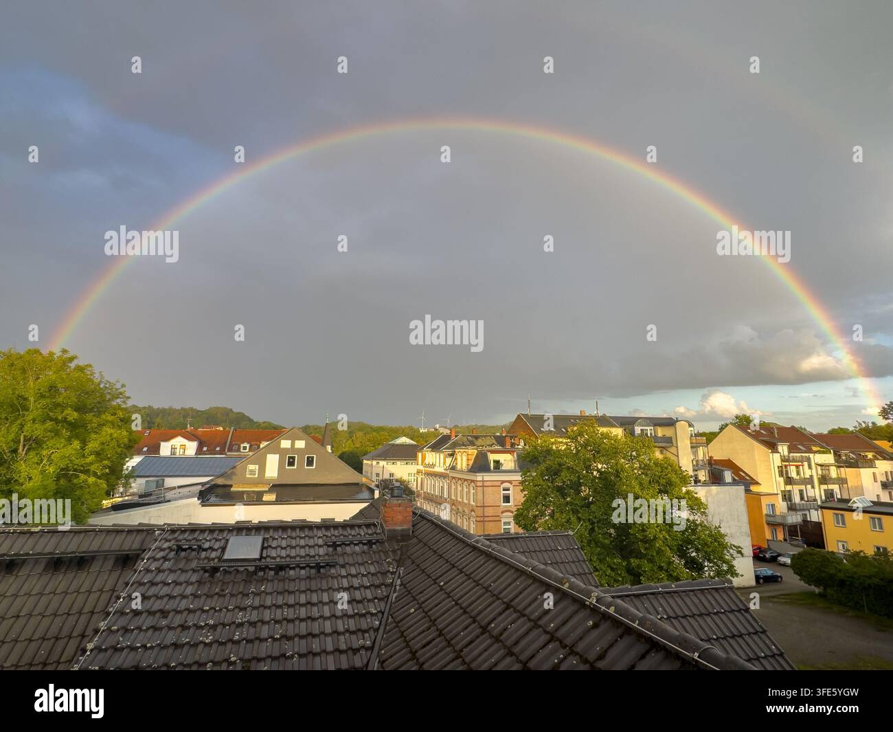 Regenbogen über Stadtdächern nach dem Regen Stockfoto