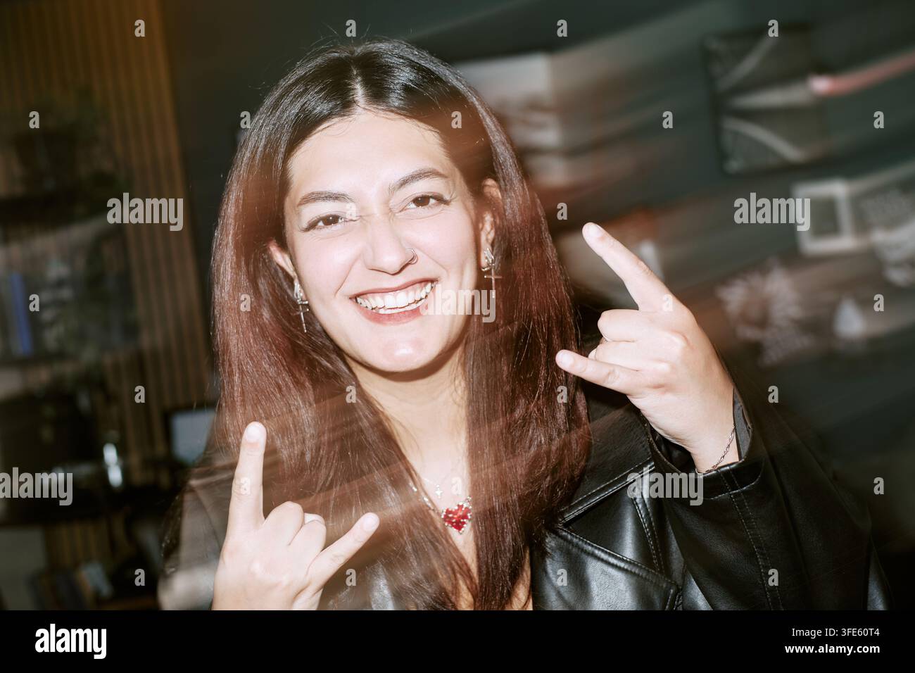 Porträt einer fröhlichen Frau, die bei einer Party das Rock-On-Zeichen zeigt Stockfoto
