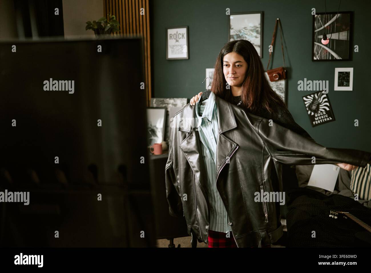 Frau hält Jacke vor dem Spiegel und wählt ein Outfit Stockfoto