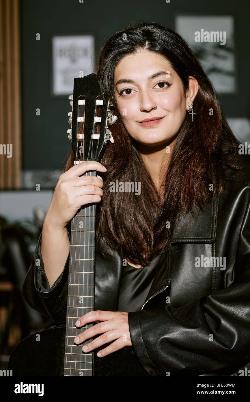 Porträt einer gemischtrassigen Frau, die im Musikstudio eine Gitarre hält Stockfoto