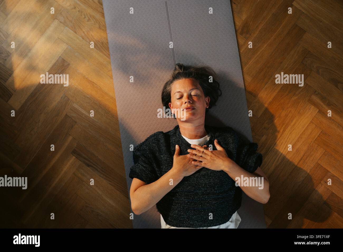 Direkt von oben aufgenommenes Bild einer Frau, die während einer Yoga-Sitzung zu Hause tief einatmet Stockfoto