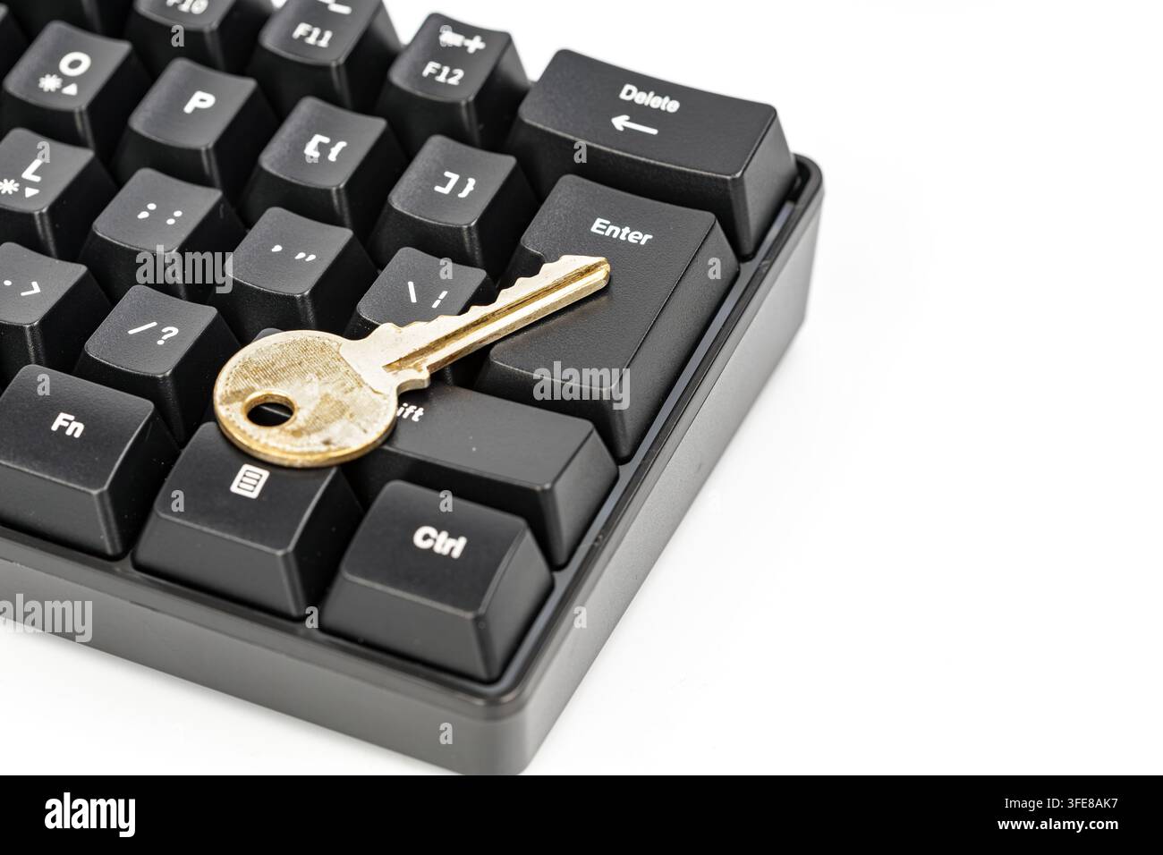 Ein goldener Schlüssel liegt auf der Eingabetaste einer schwarzen Tastatur und symbolisiert Cybersicherheit und digitale Zugriffsberechtigungen. Stockfoto