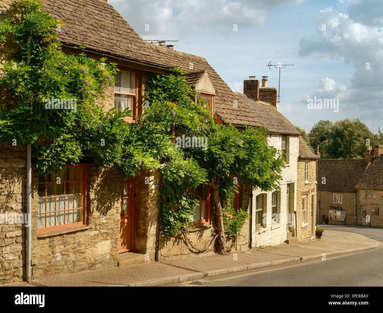 Malmesbury, Wiltshire - Die historischen Steinhäuser mit steinernen Ziegeldächern und reifer Glyzinie, die die Fassaden am unteren Ende der High Street bedeckt Stockfoto