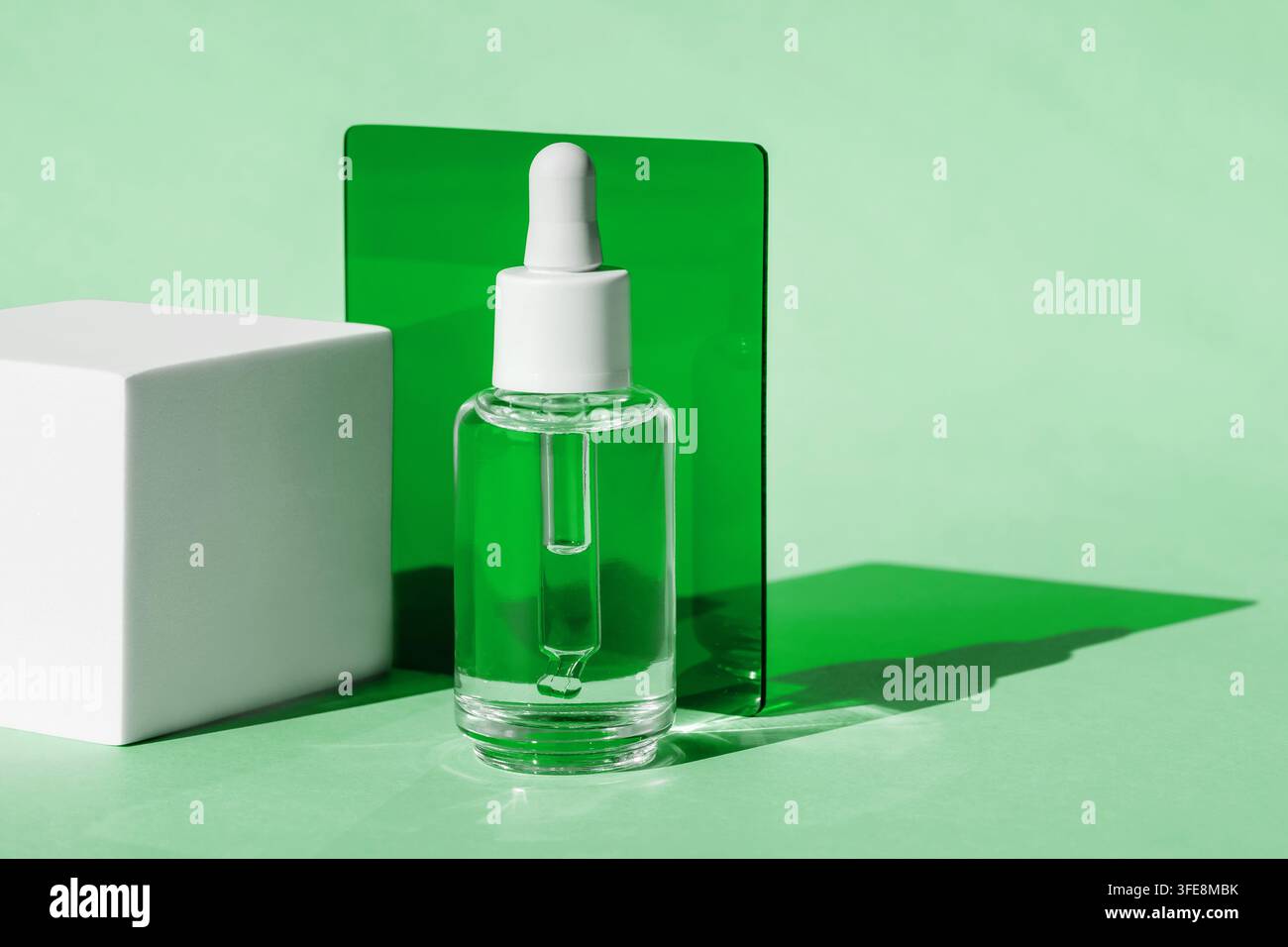Minimale Glas-Tropfflasche für Hautpflegeprodukte auf grünem Hintergrund Stockfoto