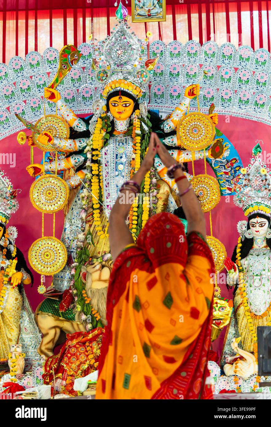 verzierte hinduistische Göttin Durga Statuen während Puja mit unscharfer Frau, die eine Hand anbietet Stockfoto