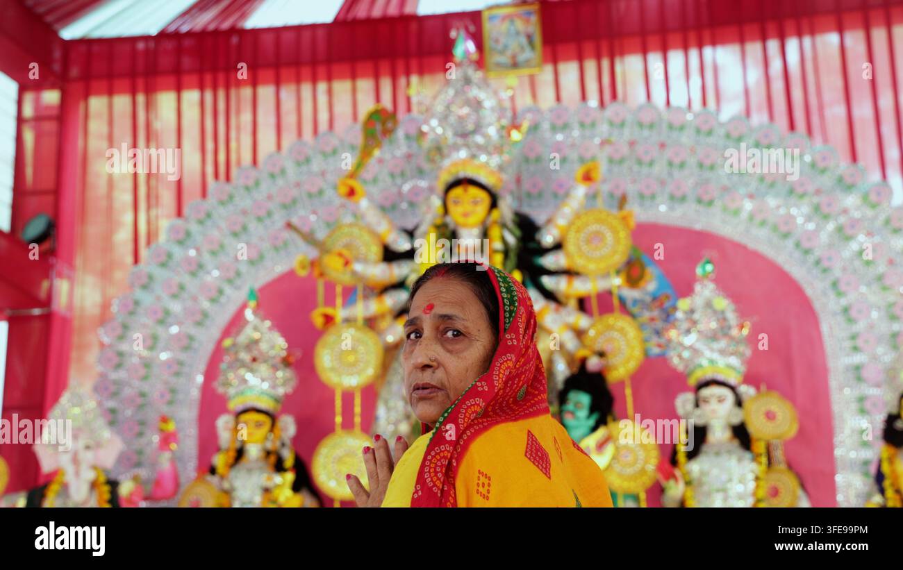 Frau, die vor farbenfrohen Göttinnenidolen beim Durga-Puja-Fest verehrt Stockfoto